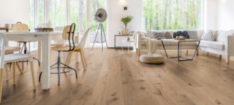 Im Wohnzimmer wurde Parkett in Langdielen-Optik verlegt. Ein Sofa und einige liebevoll platzierte Dekoelemente runden das gemütliche Ambiente ab.